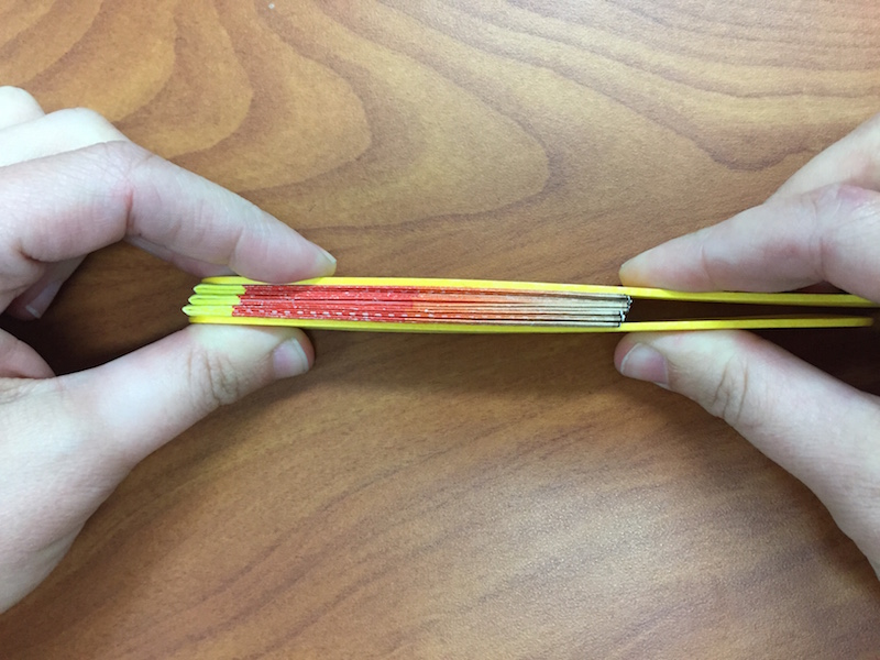 a photo of hands squeezing the compressed fan together to allow the glue to dry