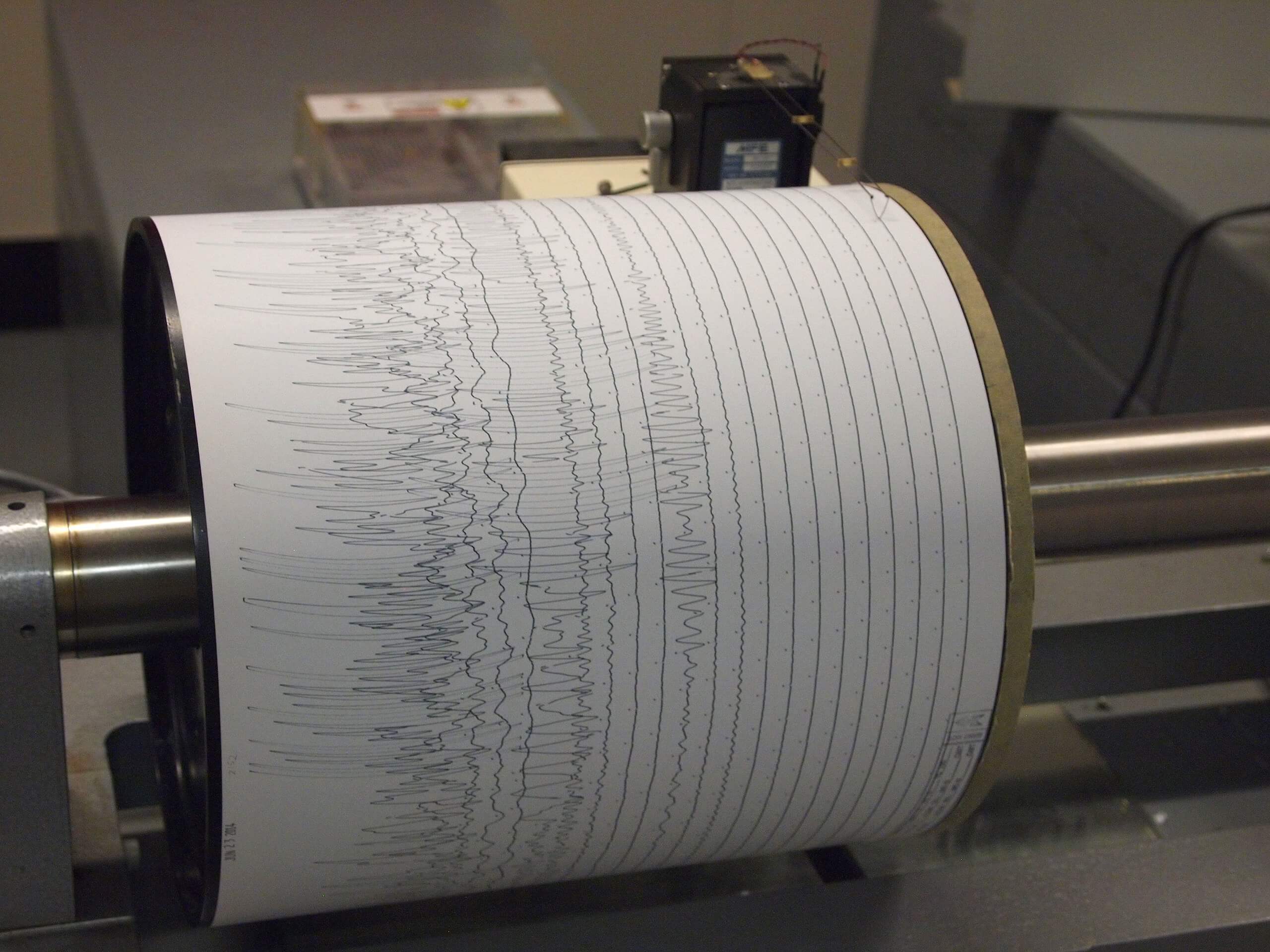 A photograph of a seismometer recording seismic waves as a series of zig-zag lines.