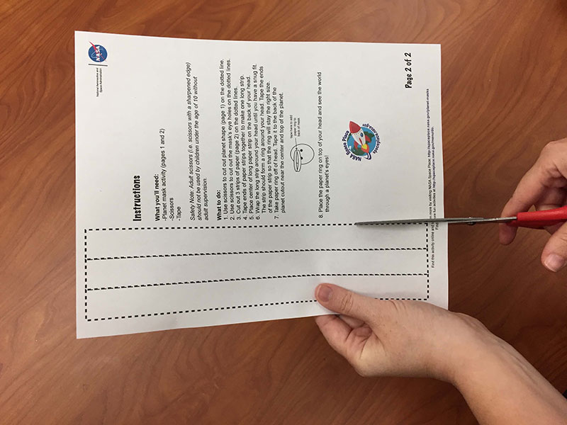 scissors cutting out strips of paper on dotted lines on activity template