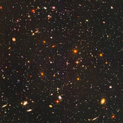 Image of small galaxies in the distance on a dark background.