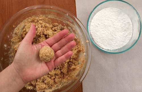 a finished cookie dough ball rests in a person's hand.