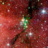 Snake? The Serpens South star cluster includes 50 young stars pulled close to each other by gravity. In this infrared Spitzer image, the stars are the green, yellow, and orange specks.