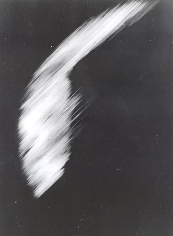 First satellite image of Earth. It is a dark picture with a single white distorted L-shaped blur.