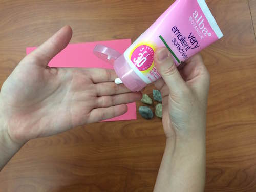 squirting a pea-sized amoung of sunscreen onto a hand