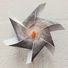 A paper pinwheel with a galaxy image printed on it.
